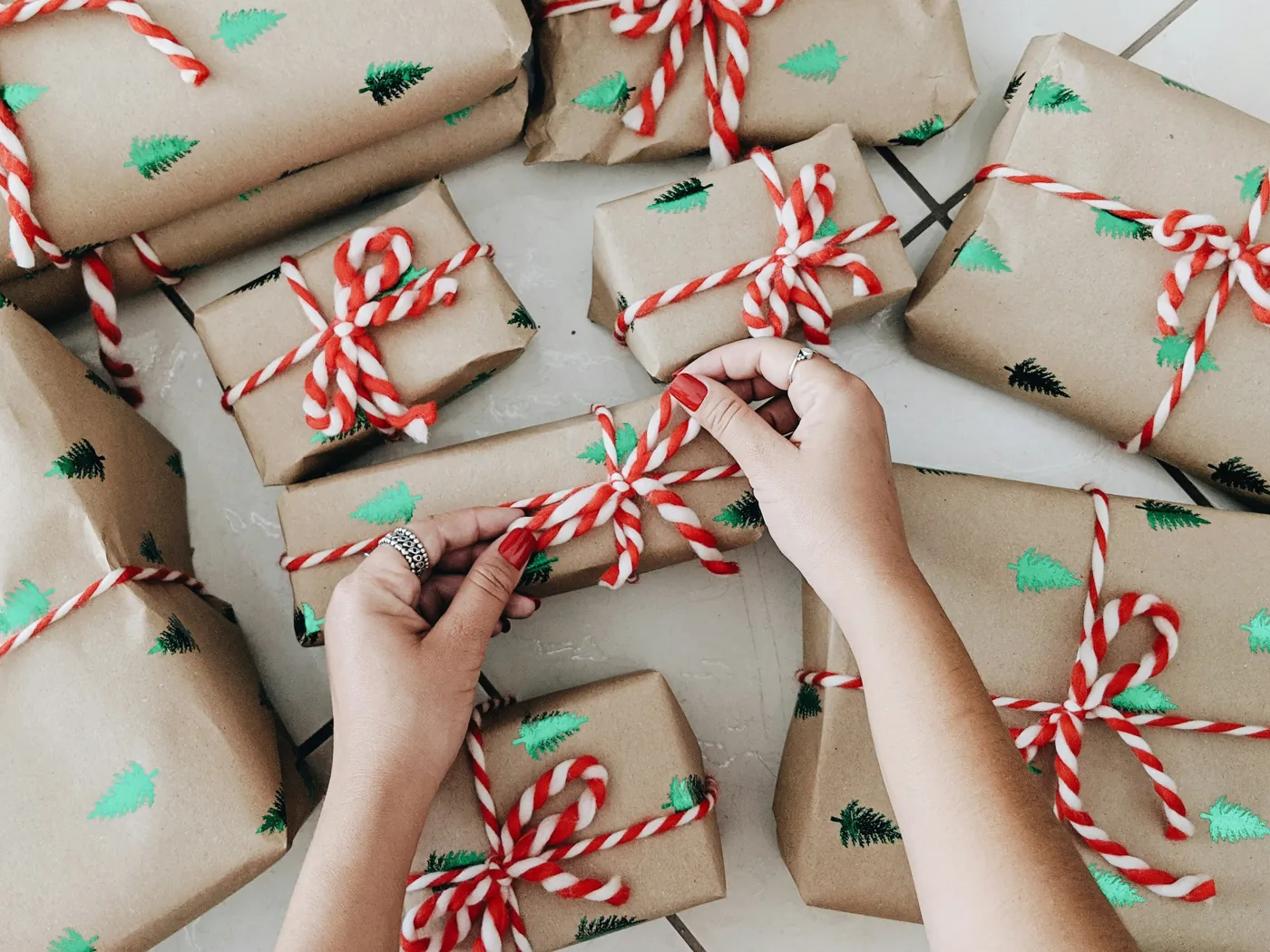 Hands tying ribbon on kraft-paper wrapped gifts